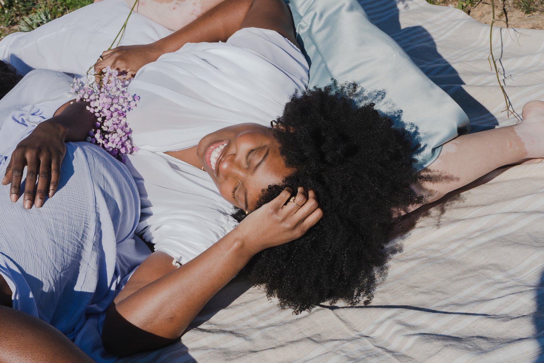 Woman with Flowers Lying on Picnic Blanket in the Field